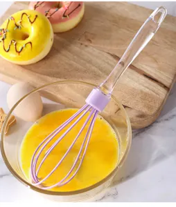 Detailansicht des manuellen Schneebesens mit lila Rührkopf in Glasschüssel zum Backen