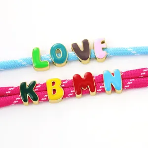 Detail shot of colorful enamel letter charms threaded on woven rope, perfect for DIY jewelry.