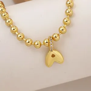 Detailed shot of 18K gold plated bubble letter pendant with matching bead chain accessory.