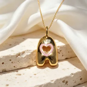 Collana con ciondolo a lettera placcato oro con dettaglio di cuore in smalto rosa chic.