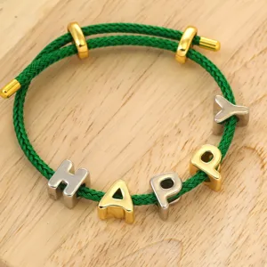 Detalle de la pulsera de cuerda trenzada verde con cuentas de letras metálicas doradas y plateadas.