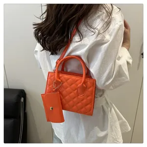 Close-up of orange quilted crossbody bag showing fine texture and mini pouch detail.