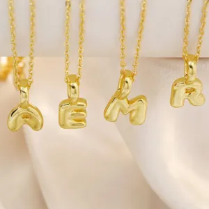 Close-up view of gold-plated brass letter pendant necklace showing detailed metal craftsmanship.