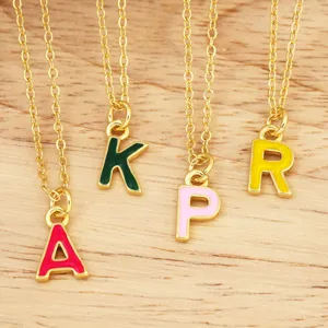 Primo piano di catene dorate con ciondoli di lettere smaltate colorate A K P R gioielli DIY.