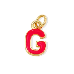 Dettaglio in primo piano del ciondolo lettera G smaltato rosso dorato per gioielli fai da te.