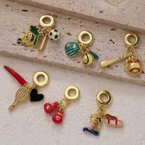 Gros plan détail des pendentifs de sport dorés, breloque émail baseball et football pour bracelet.
