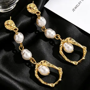 Close-up of elegant gold baroque pearl drop earrings with hammered metal texture