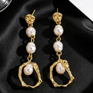 Close-up detail of elegant vintage gold-tone drop earrings featuring white baroque pearls