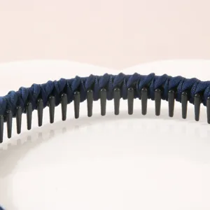 Dettaglio ravvicinato di un cerchietto avvolto in tessuto blu scuro con sottili denti neri.