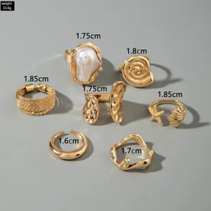 Vue détaillée de l'ensemble de 7 bagues dorées sur le thème marin avec coquillage, perle et étoile.