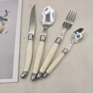 Detailed view of ivory white Laguiole style stainless steel cutlery set with bee emblem.
