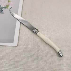 Close-up of engraved bee detail and ivory white handle on a stainless steak knife