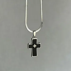 Primer plano de un colgante de cruz negra Y2K gothic punk en un collar de cadena de serpiente