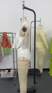 Side view of white halter neck bodysuit with sheer lace back detail on mannequin