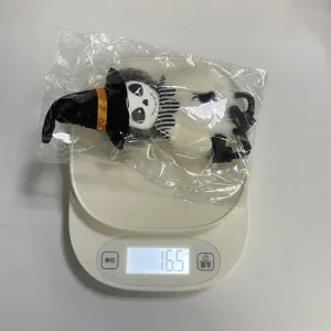 Vue détaillée montrant le poids léger de la peluche sorcière d'Halloween sur une balance électronique