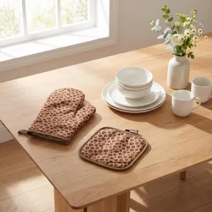 Professional leopard print oven mitt and square pot holder set on a natural wooden kitchen table