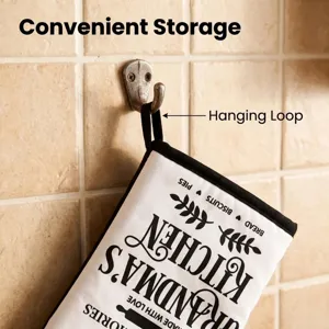 Close-up of white oven mitt with hanging loop on a wall hook for convenient storage.