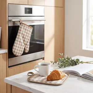 Detailed view of beige checkered oven mitt and pot holder in a modern kitchen setting