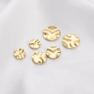 Close-up of golden irregular hammered round plate pendants with side holes for DIY jewelry.