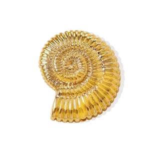 Primo piano ciondolo conchiglia ammonite oro, texture metallica lucida, dettaglio gioiello.