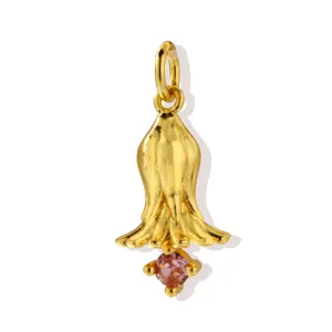 Close up detail of a golden flower pendant necklace accessory featuring a sparkling pink zircon stone.