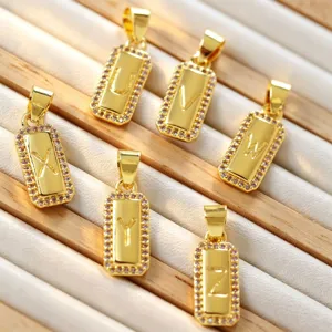 Primo piano dettagliato di ciondoli con lettere rettangolari placcati in oro 18k con zirconi.