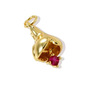 Detail shot of a gold-plated brass flower pendant featuring a sparkling red birthstone zircon.