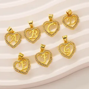 Detailed shot of gold plated heart letter pendants with pavé crystal stones, shiny and elegant style.
