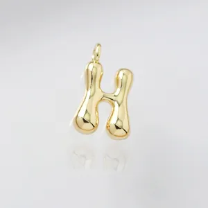 Gold puffy letter H pendant detail close up glossy metal charm necklace accessory element