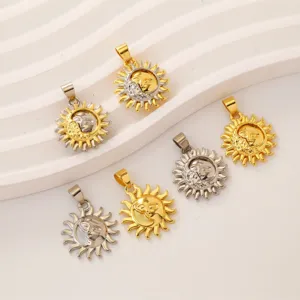 Gros plan de pendentifs breloques en métal visage de soleil en finition bicolore or et acier.