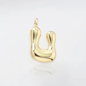 Gold puffed alphabet letter pendant closeup detail shot showing shiny metal surface texture.