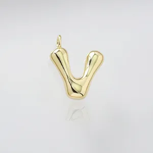Close up detail of gold puffed letter V pendant, elegant shiny metallic finish charm.