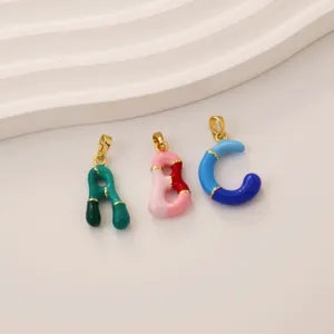 Close-up detail of colorful enamel alphabet letter pendants, featuring shiny gold-plated bails.
