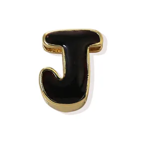 Detailed close-up of letter J black enamel gold plated pendant charm fashion accessory.