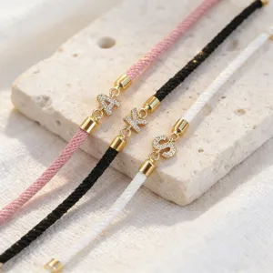 Primo piano dettagliato del bracciale in corda intrecciata con lettere iniziali e zirconi.