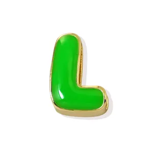 Detail shot of the gold plated letter L pendant featuring vibrant green enamel filling.
