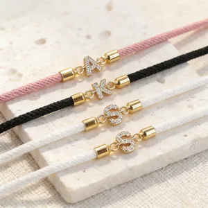 Primo piano di bracciali in corda Milan con iniziali fai-da-te e ciondoli zirconati luminosi.