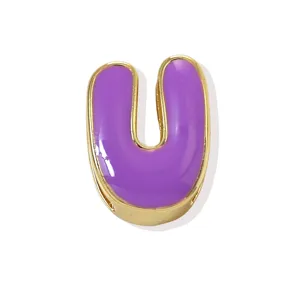 Close-up detail of the gold-plated copper letter U pendant with purple enamel finish.
