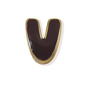 Close-up detail of the gold-plated copper enamel letter V charm pendant, smooth surface.