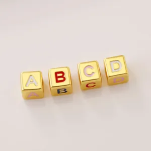 Gold square alphabet beads close-up, colorful enamel letter details for DIY jewelry making.