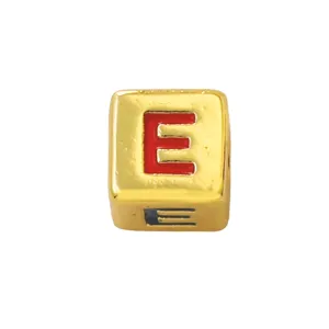 Close-up detail of a gold square alphabet charm bead with red enameled letter E for DIY jewelry.