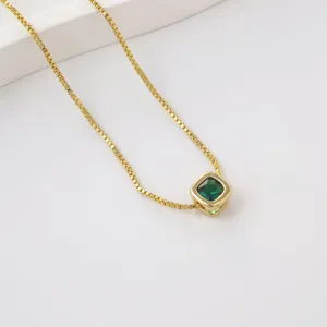 Gold square green gemstone pendant necklace on box chain, elegant minimalist jewelry detail view.