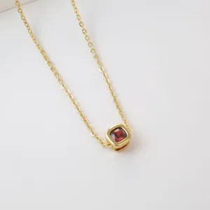 Gold brass necklace featuring a red square cubic zirconia pendant, elegant jewelry detail view.