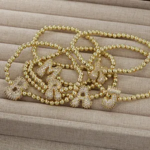 Nahaufnahme Detail des Goldperlen Armbands mit klobigen glitzernden Zirkon Buchstaben Anhängern.
