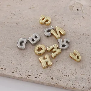 Close-up van glimmende goud- en zilverkleurige pufferige letterbedels op gestructureerde steen.