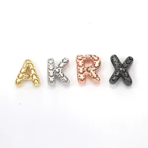 Gros plan de charms lettres alphabet en métal avec design smiley creux, quatre couleurs.