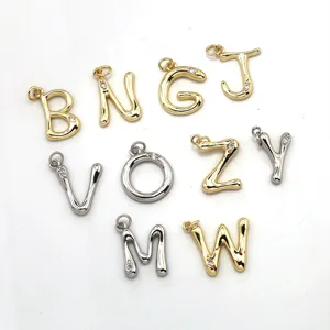 Detailed view of creative brass letter charms with gold and silver plating and sparkling stone accents.
