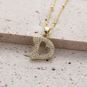 Collier pendentif lettre en zircon doré gros plan, bijou étincelant délicat et élégant.