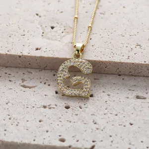 Gros plan sur un collier en cuivre plaque or avec pendentif lettre G en zircons cubes.