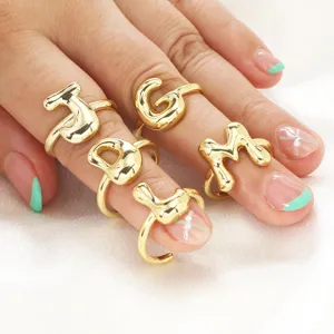 Dettaglio in primo piano dell'anello con lettera dorata, superficie lucida e design elegante.